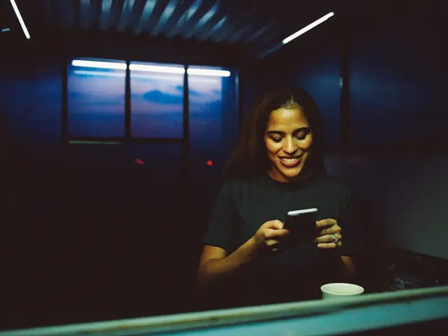Dona de cafeteria sorrindo ao ler uma mensagem no celular no fim do expediente