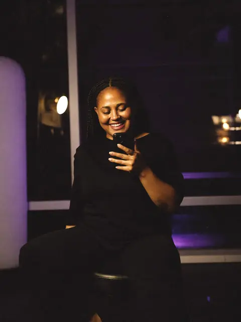 Dona de um pequeno estúdio de beleza sorrindo ao ler uma mensagem no celular