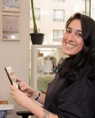 Dona de loja de roupas sorrindo com o celular na mão