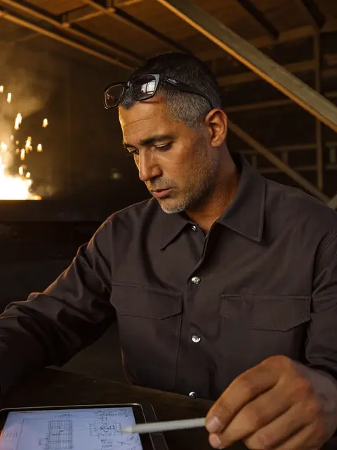 Engenheiro de produção conferindo um desenho técnico no tablet dentro da fábrica