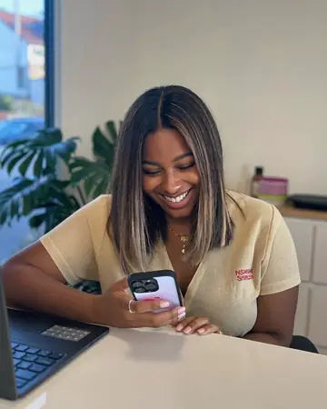 Dona de clínica de estética lendo uma mensagem no celular na recepção